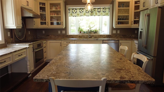 38648 Masumola Rd, Polson, MT 59860 - kitchen with a breakfast bar area, a center island, under cabinet range hood, cream cabinets, and stainless steel appliances