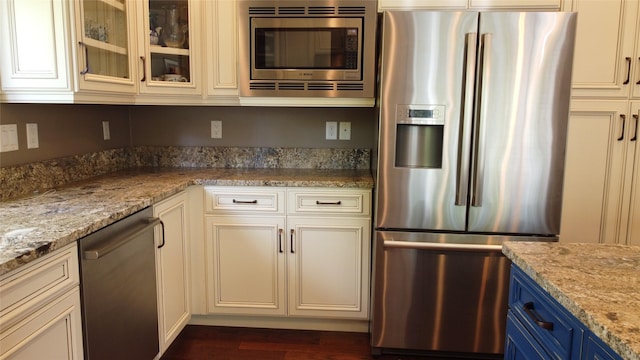 38648 Masumola Rd, Polson, MT 59860 - kitchen featuring blue cabinetry, dark wood-style floors, light stone countertops, appliances with stainless steel finishes, and glass insert cabinets