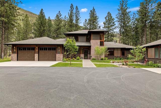 prairie-style house with an attached garage, brick siding, and driveway