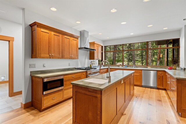 kitchen featuring light hardwood / wood-style flooring, kitchen peninsula, a breakfast bar area, wall chimney exhaust hood, and sink