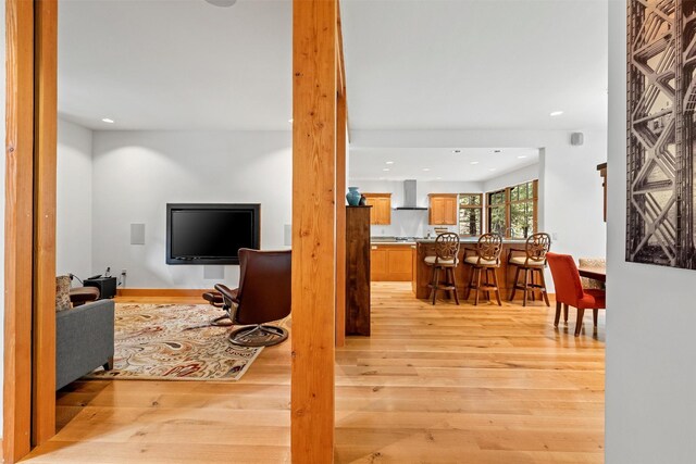 kitchen featuring light hardwood / wood-style floors, butcher block countertops, wall chimney exhaust hood, built in appliances, and sink