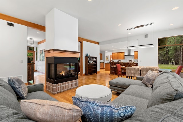 living room featuring a multi sided fireplace and light hardwood / wood-style flooring