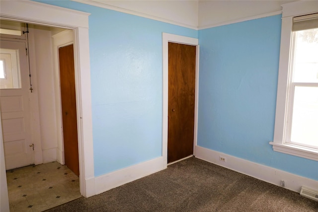 carpeted empty room featuring plenty of natural light and ornamental molding