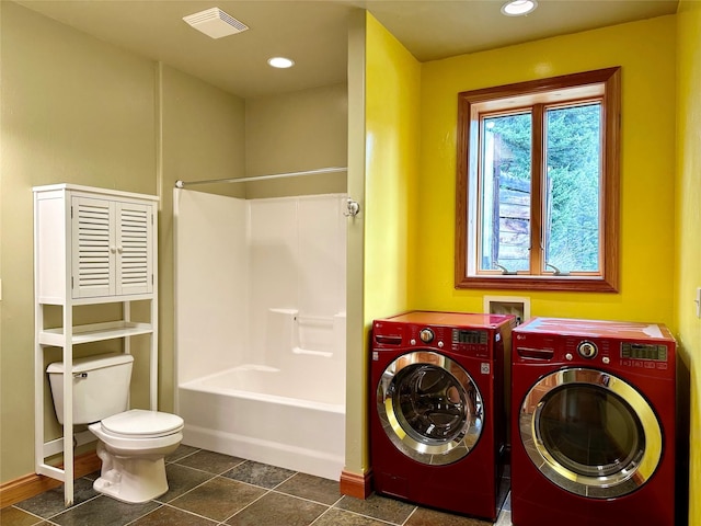 laundry room with washer and clothes dryer and dark tile patterned flooring