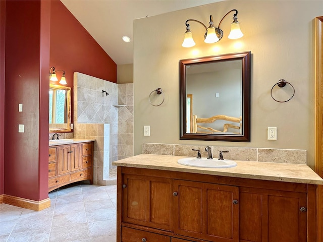 bathroom featuring tile patterned flooring, vanity, lofted ceiling, and a tile shower