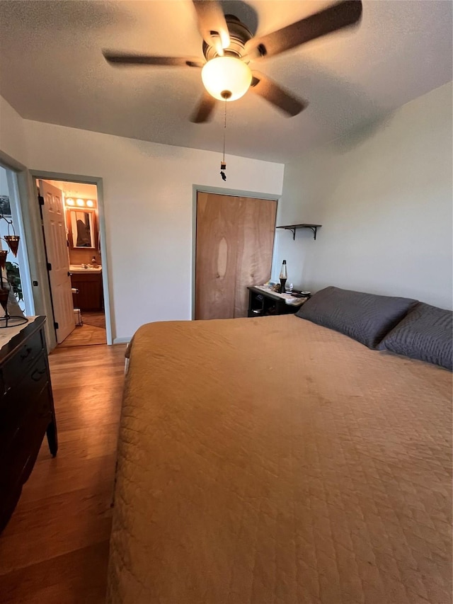 bedroom with a textured ceiling, connected bathroom, light hardwood / wood-style floors, and ceiling fan