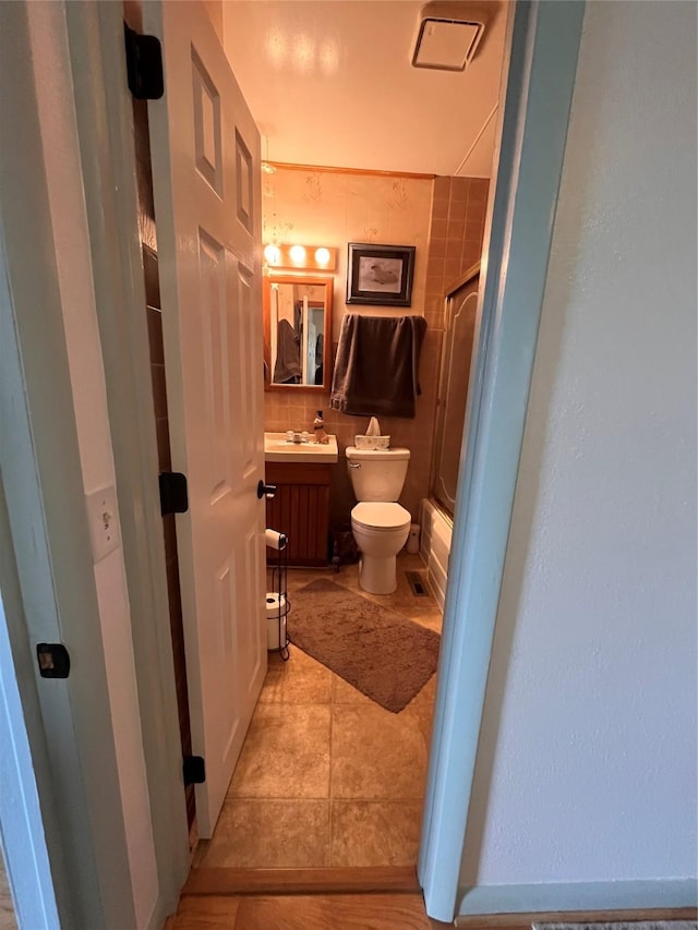 full bathroom featuring tile patterned flooring, vanity, toilet, and combined bath / shower with glass door