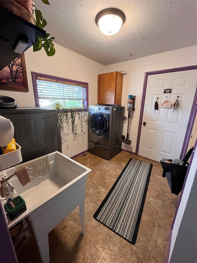 laundry area with cabinets, a textured ceiling, and washing machine and dryer