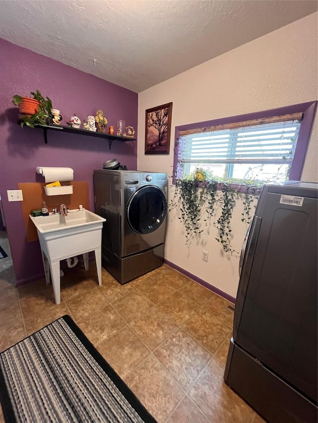 clothes washing area featuring a textured ceiling, separate washer and dryer, and light tile patterned flooring