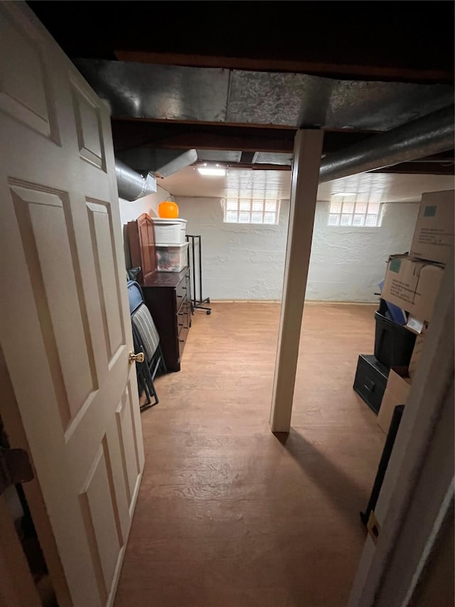 basement with a healthy amount of sunlight and light hardwood / wood-style floors