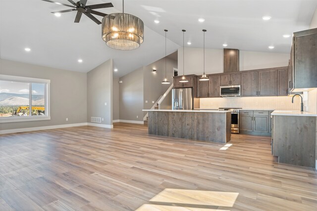 kitchen with pendant lighting, high vaulted ceiling, stainless steel appliances, and a kitchen island