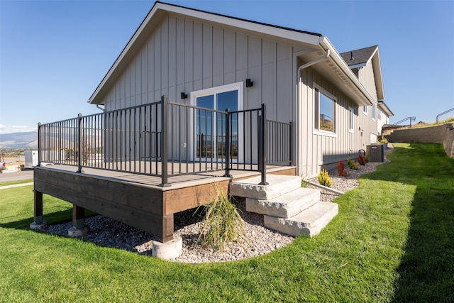 rear view of property featuring central AC unit, a deck, and a yard