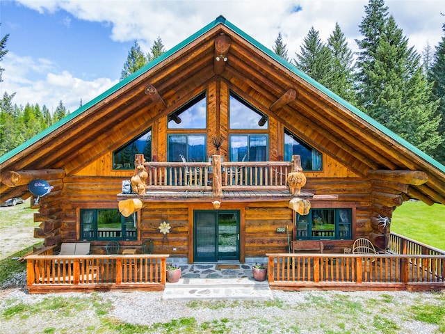 log-style house featuring a garage, a balcony, and an outbuilding