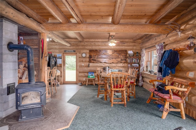 dining area with a wood stove, rustic walls, and wood ceiling