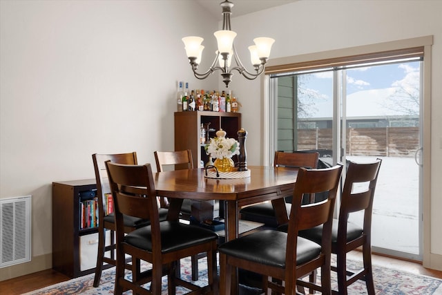 dining room with an inviting chandelier, visible vents, and light wood finished floors