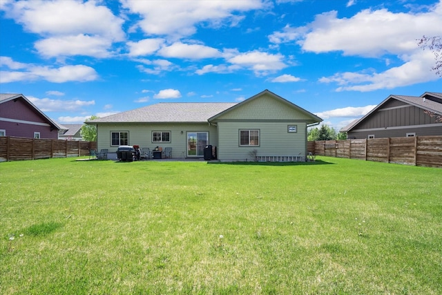 rear view of house featuring a fenced backyard and a lawn