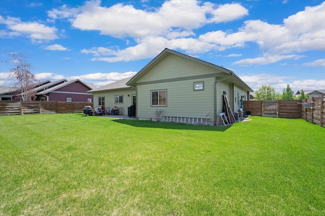 back of property with a fenced backyard, a yard, and a patio