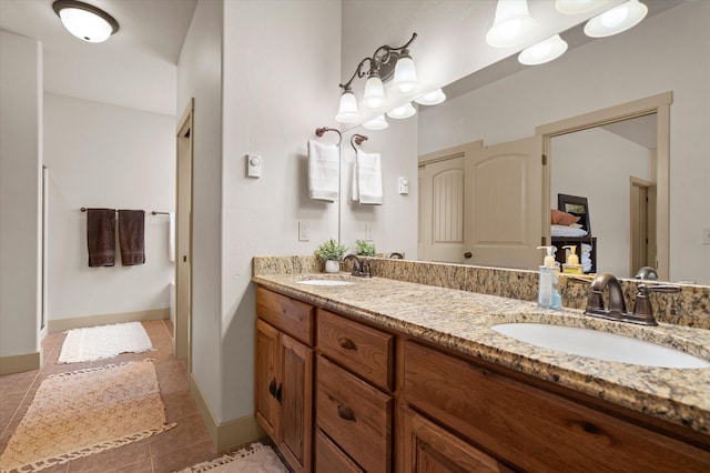 bathroom with baseboards, double vanity, a sink, and tile patterned floors