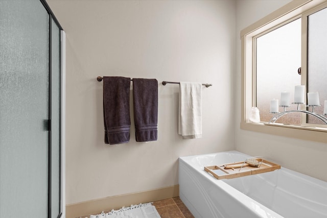 full bathroom with tile patterned flooring, baseboards, and a bath