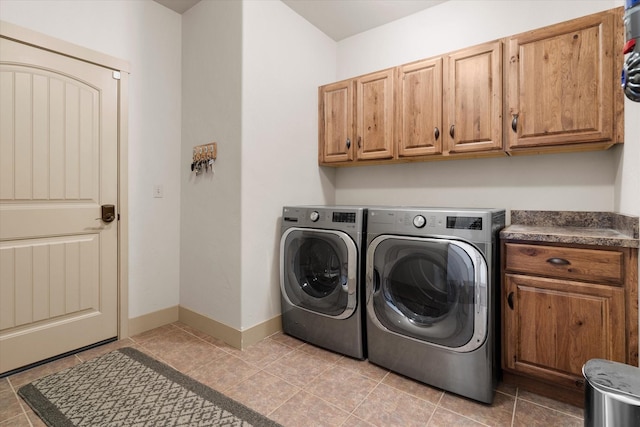 washroom featuring baseboards, cabinet space, washing machine and clothes dryer, and light tile patterned flooring