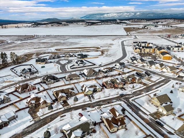 snowy aerial view featuring a residential view and a mountain view