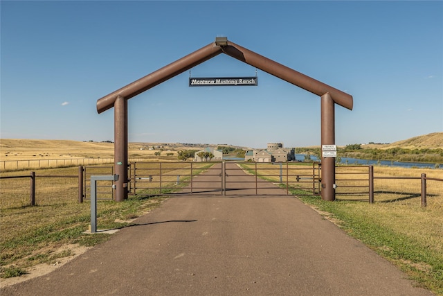 view of gate with a yard and a rural view