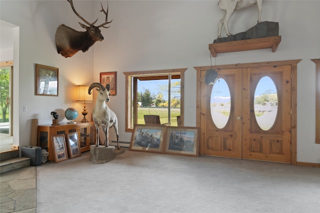 entrance foyer featuring carpet flooring, a towering ceiling, and a baseboard heating unit