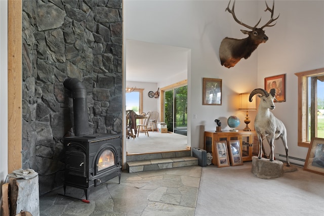 entrance foyer with baseboard heating, carpet, and a wood stove