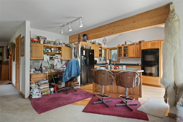 kitchen featuring lofted ceiling with beams, a kitchen island, black appliances, track lighting, and a kitchen bar