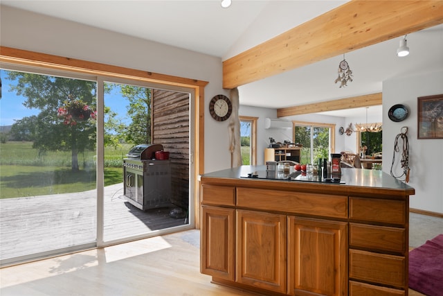 kitchen with light hardwood / wood-style floors, pendant lighting, an AC wall unit, lofted ceiling with beams, and a wood stove