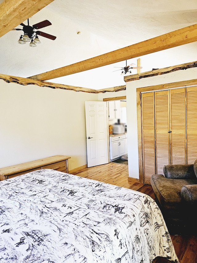 bedroom featuring beamed ceiling, ceiling fan, light hardwood / wood-style floors, and a closet