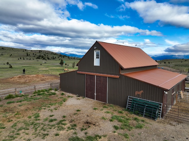 view of home's exterior with a mountain view, an outbuilding, and a rural view