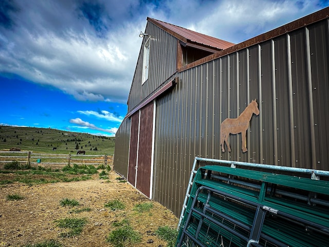 view of property exterior with a rural view and an outdoor structure