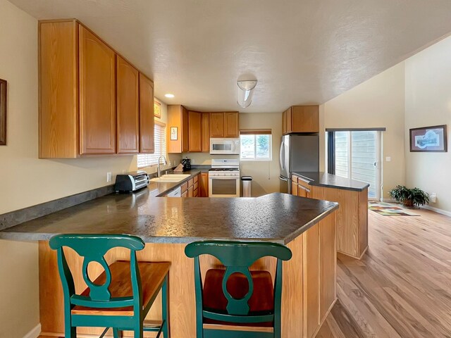 living room with light hardwood / wood-style flooring, high vaulted ceiling, and sink