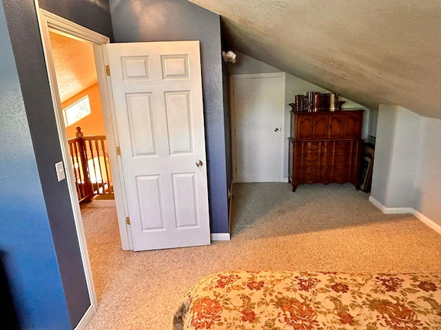 unfurnished bedroom with a textured ceiling, light colored carpet, and lofted ceiling