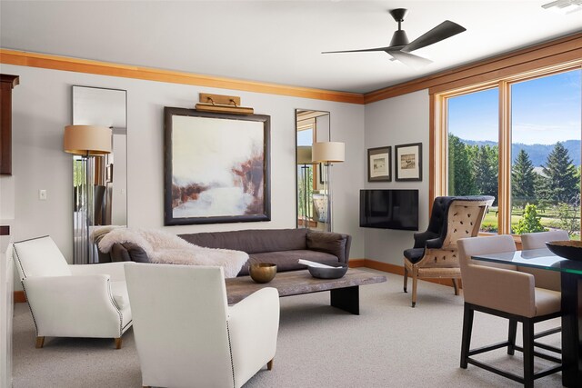 carpeted living room featuring ornamental molding and ceiling fan