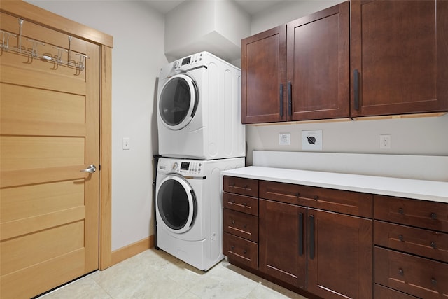 clothes washing area featuring cabinets and stacked washer / dryer