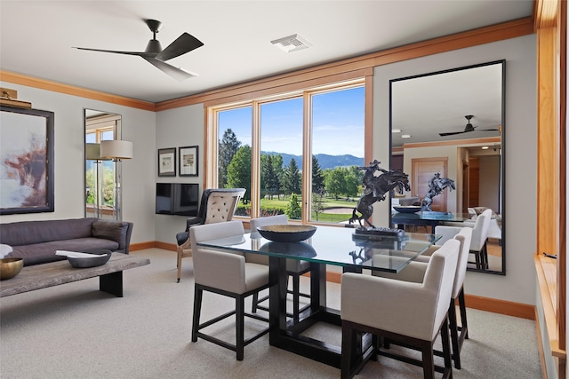 carpeted dining space featuring a mountain view, ornamental molding, and ceiling fan