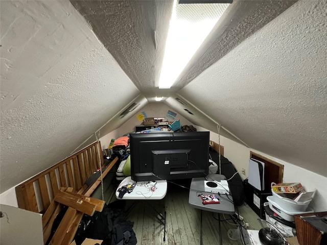 bonus room with hardwood / wood-style floors, lofted ceiling, and a textured ceiling