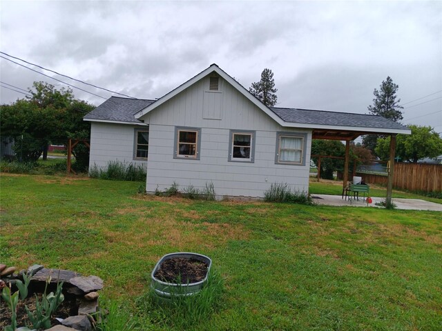 view of side of home with a patio and a lawn