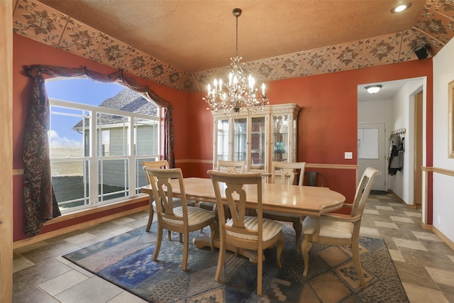 dining room featuring a notable chandelier, tile flooring, and a textured ceiling