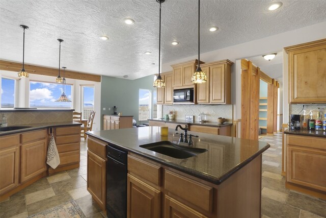 kitchen featuring decorative light fixtures, backsplash, a center island with sink, black appliances, and sink