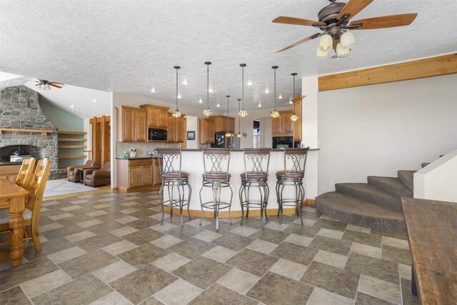 kitchen featuring ceiling fan, pendant lighting, black appliances, tile floors, and lofted ceiling