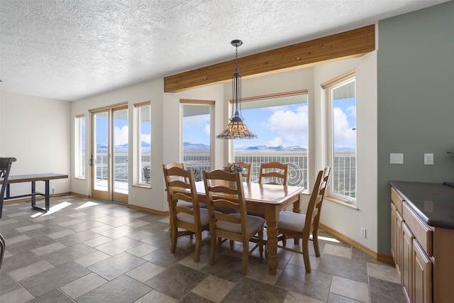 dining room with plenty of natural light, dark tile floors, and a textured ceiling