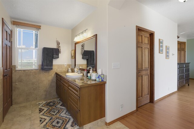 bathroom with wood-type flooring, vanity, and tile walls