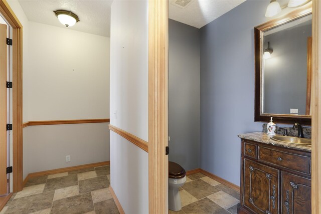 bathroom with tile floors, a textured ceiling, toilet, and vanity