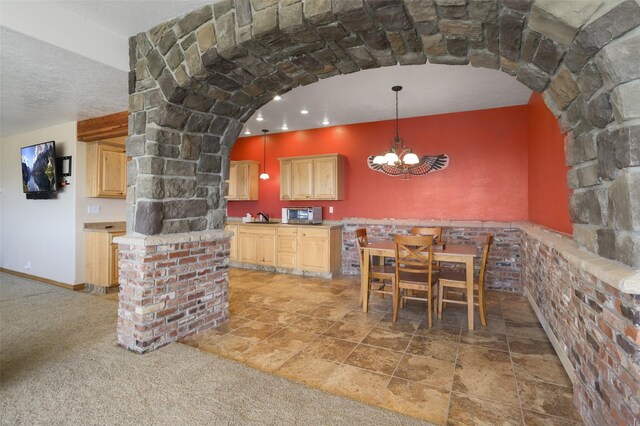 kitchen featuring decorative light fixtures, light brown cabinetry, carpet, sink, and a chandelier