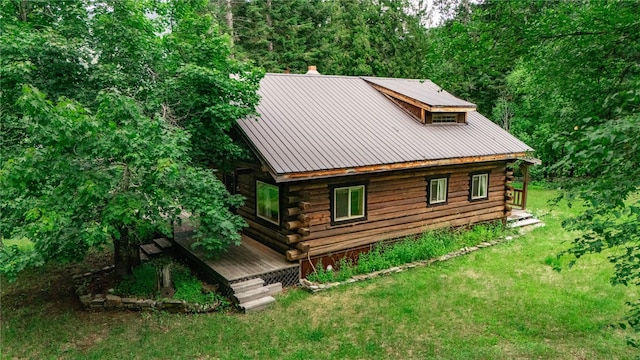 view of home's exterior with metal roof, a lawn, a standing seam roof, and log siding