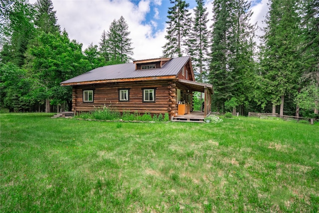 rear view of house featuring metal roof, log exterior, and a yard