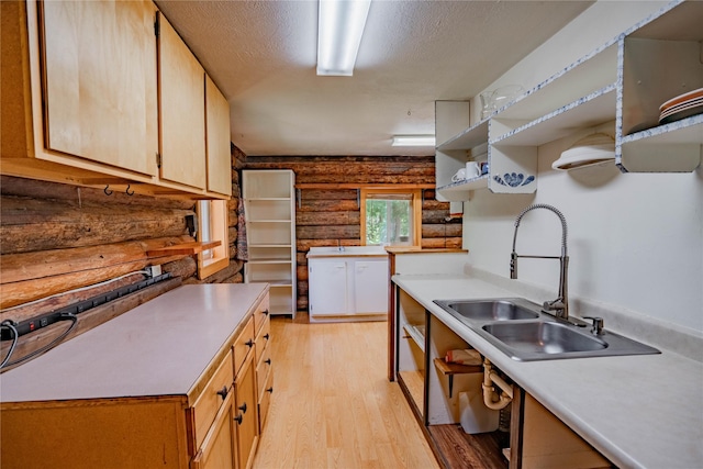 kitchen featuring light countertops, a textured ceiling, light wood-type flooring, open shelves, and a sink